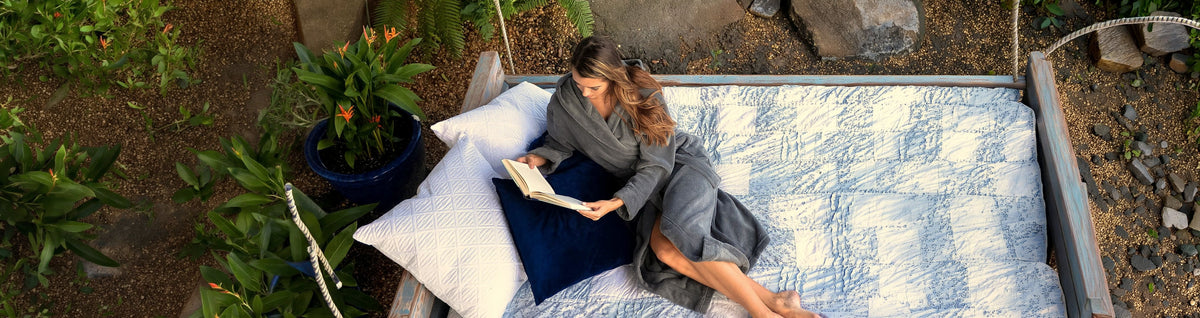 Woman reading on a garden swing bed in a gray Alexander Del Rossa plush fleece robe